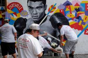 Employees of Joe's Pizza build a makeshift memorial to the late Muhammad Ali near a mural in New York